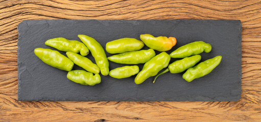 Green cheiro peppers on a stone board over wooden table. Typical brazilian ingredient