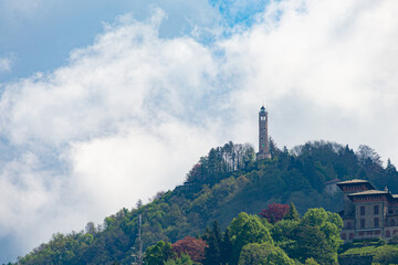 Fototapeta na wymiar The famous lighthouse on a hill in front of Como, Italy, located in a village called Brunate. Blue sky and white clouds on the background.