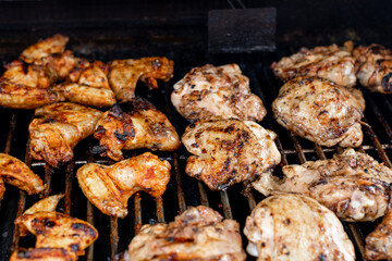 Bbq chicken wings and thighs on a barbecue grill cooking with a nice chargrilled finish, shallow depth of field advertising image