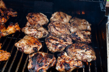 Bbq chicken thighs on a barbecue grill cooking with a nice chargrilled finish, shallow depth of field advertising image