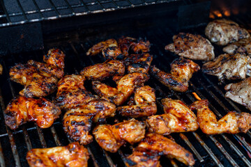 Bbq chicken wings on a barbecue grill cooking with a nice chargrilled finish, shallow depth of field advertising image