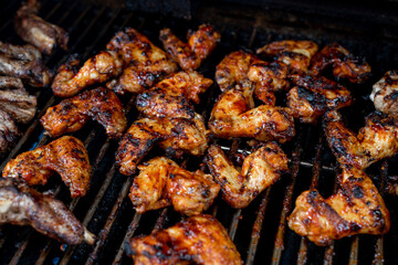 Bbq chicken wings on a barbecue grill cooking with a nice chargrilled finish, shallow depth of field advertising image