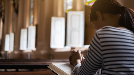 Christian woman praying on holy bible in the public church. Woman pray for god blessing to wishing have a better life and believe in goodness.