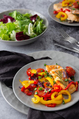 Baked red fish fillet Arctic char on a plate with vegetables, mix salad in a bowl, delicious hearty healthy dinner
