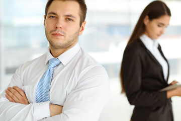 Portrait of a self-confident middle-aged businessman, standing with his colleague in the background. Business concept