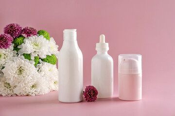 Mock up natural cosmetics: serum, cream, mask for advertising on light pink background with flowers. Organic products.