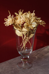 A glass vase with a bouquet of flowers made from straw on a red background