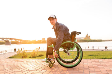 Fototapeta premium Young man in wheelchair and his friend walk outdoors