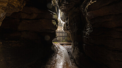 Narrow passage between big rocks in stone labyrinth Bledne skaly, Szczeliniec Wielki in National Park Stolowe Mountains, Poland. misty weather. - obrazy, fototapety, plakaty
