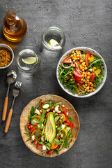 Various summer healthy vegetables salads with avocado, cucumber, radish, bell pepper and tomato on grey background. Healthy food.