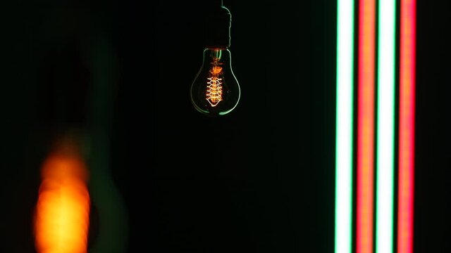 Electric light bulb on a black background. Thomas Jefferson light bulb lamp over black background with colourful led stripes.