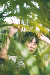 Portrait of young adult asian woman in home garden with tree leaf.
