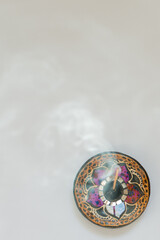 Colorful incense stick holder seen from above with swirling smoke.