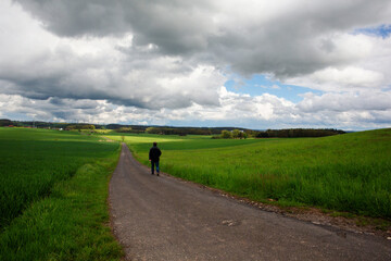 Man walking in Bavaria on a country road and getting healthy exercise