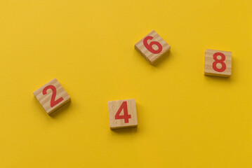 Wooden block with number two, four, six and eight on yellow background.