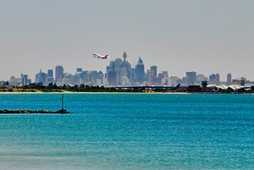 Southern view of the Sydney skyline as a plane takes off on a hazy summer day, seen from the...