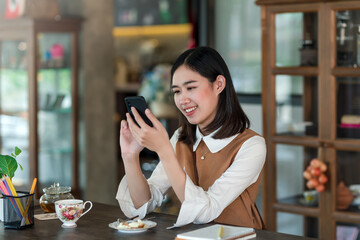 Asian businesswoman lounging at a coffee shop using a smartphone.
