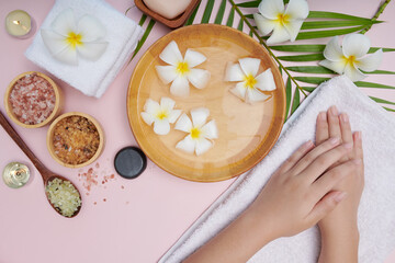 Obraz na płótnie Canvas Young woman applying natural scrub on hands against white background. Spa treatment and product for female hand spa, massage, perfumed flowers water and candles, Relaxation. Flat lay. top view.