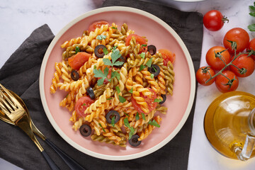 Three Colors Rotini Pasta.  Abstract texture of colorful pasta. Pattern of macaroni. Tasty appetizing classic italian spaghetti pasta with tomato sauce, cheese and basil on plate.