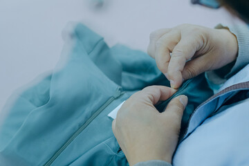 Woman tailor hands sewing on blue fabric cloth