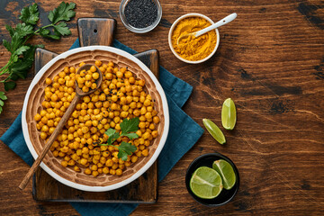 Fried chickpeas with turmeric in ceramic plate on an old wooden table background. Roasted spicy chickpeas or Indian chana or chole, popular snack recipe. Top view.