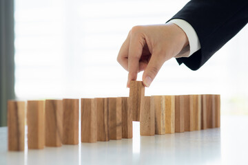 Businesswoman protect wooden block fall to planning and strategy in risk to business Alternative...
