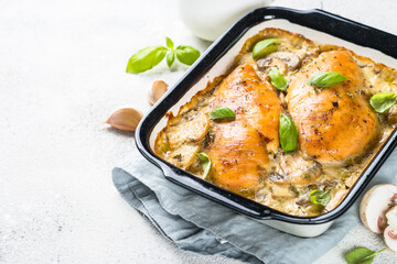 Baked chicken breast with mushrooms in cream sauce on white kitchen table.