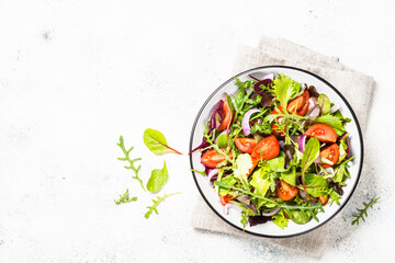 Green salad from fresh salad leaves and vegetables in white plate. Healthy vegan food. Top view image.