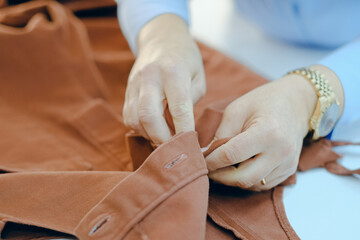 Woman working with textile while buttoning a brown coat