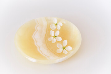 Three beautiful white flowers of apple tree on an onyx plate.