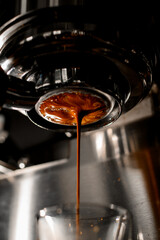 Delicious freshly ground espresso pouring through bottomless portafilter into glass.