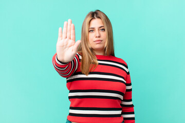 curvy pretty blonde woman looking serious showing open palm making stop gesture