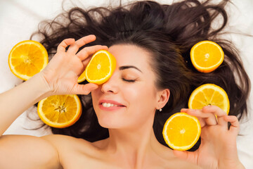 Pretty charming joyful attractive cheerful positive young woman with pieces of orange,