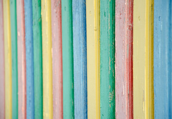 Selective focus multi-colored palisade made of wooden boards. The texture of cracked old paint on wooden planks. The surface of the playground fence. Cozy concept..