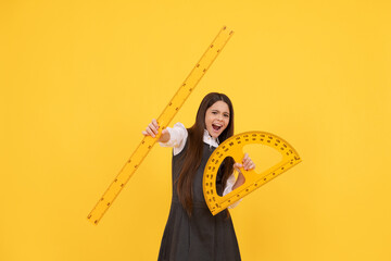 emotional child hold math protractor and ruler in school on yellow background, education