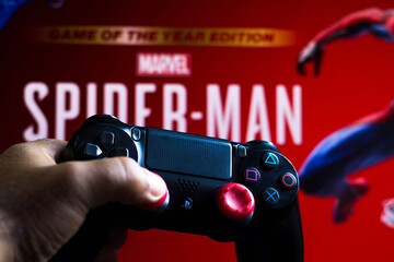 Naklejka premium May 17, 2021, Brazil. In this photo illustration the controller for PlayStation (PS) and in the background the game logo Spider-Man.