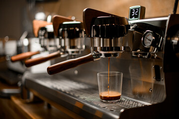 professional coffee machine automatically prepares and pours espresso drink into clear glass