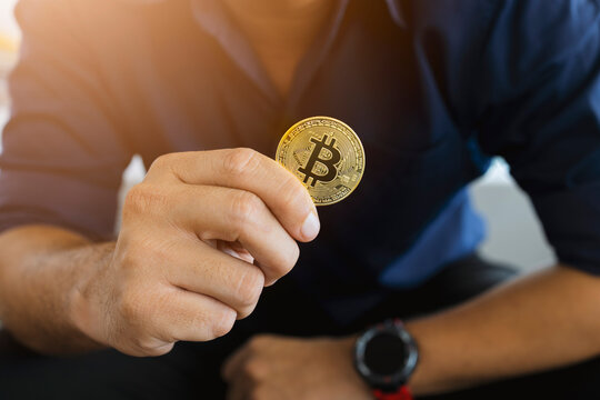 golden bitcoin in a businessman hand in the office with soft focus and backlighting. cryptocurrency concept