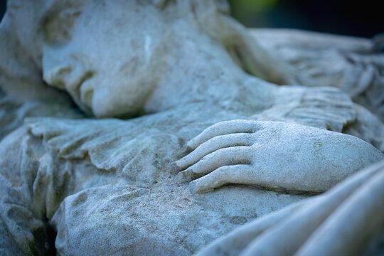 Death. Fragment of an ancient statue of end of human life. Beautiful dead woman light on the bed. Selective focus on hand.