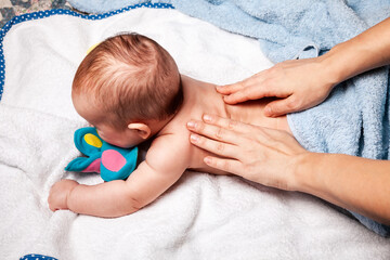 Little baby receiving chiropractic treatment of her back at home - obrazy, fototapety, plakaty