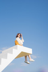 asian woman sit on white stair in flower garden on springtime vacation