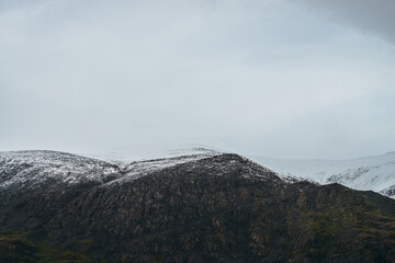 Minimalist highlands landscape with snow-capped mountains under cloudy sky. Snowbound high mountain...