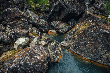 Scenic nature background of turquoise clear water stream among rocks with mosses and lichens. Atmospheric mountain landscape with mossy stones in transparent mountain creek. Beautiful mountain stream.