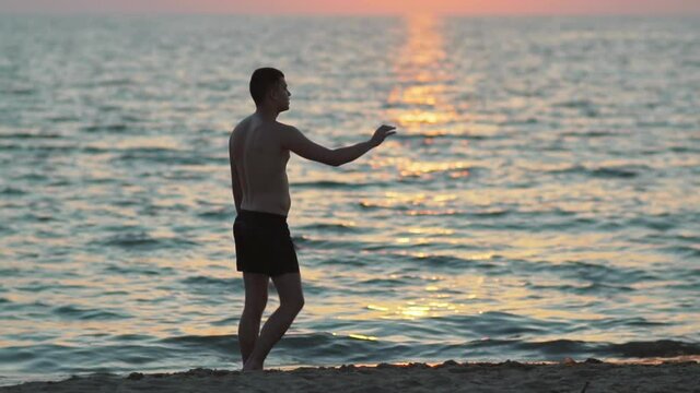 Slow motion of a fit man playing frisbee on the beach. Vacation concept