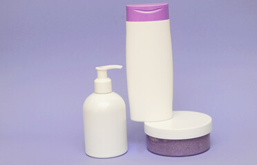 Group of cosmetic bottles with lilac on background.  Face scrub, gel shower and cream on violet background with lilac flowers.