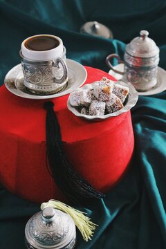 ethnic still life image of traditional ottoman empire fez, turkish coffee cup and plate with silver arabesque patterns carved & turkish delight 