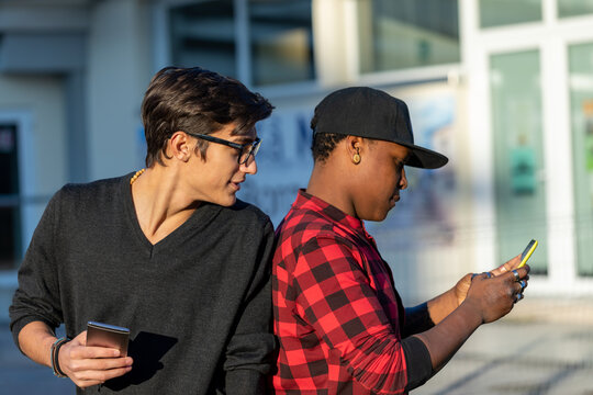Young man reading a friends phone messages over his shoulder
