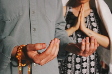 two people , interreligious couple praying together , muslim and christian prayer hand gestures...