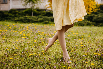 Closeup of female barefoot feet, walking in a field with green grass and flowers.