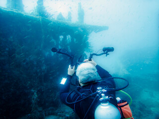 A diver photographs a sunken ship at the bottom of the Indian Ocean